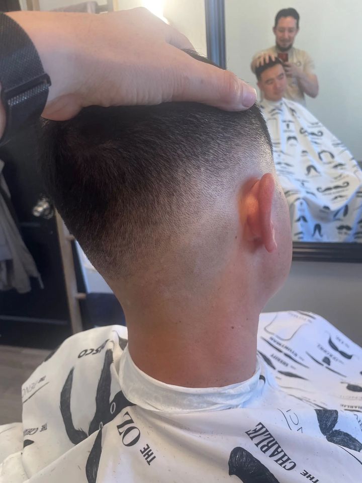 Low skin fade from behind, with JP visible in the mirror