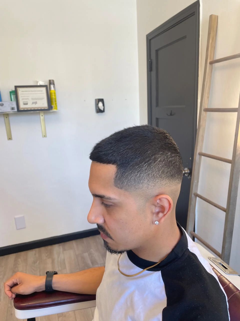 Client in the studio chair showing a fresh skin fade with a sharp line-up, cut by JP