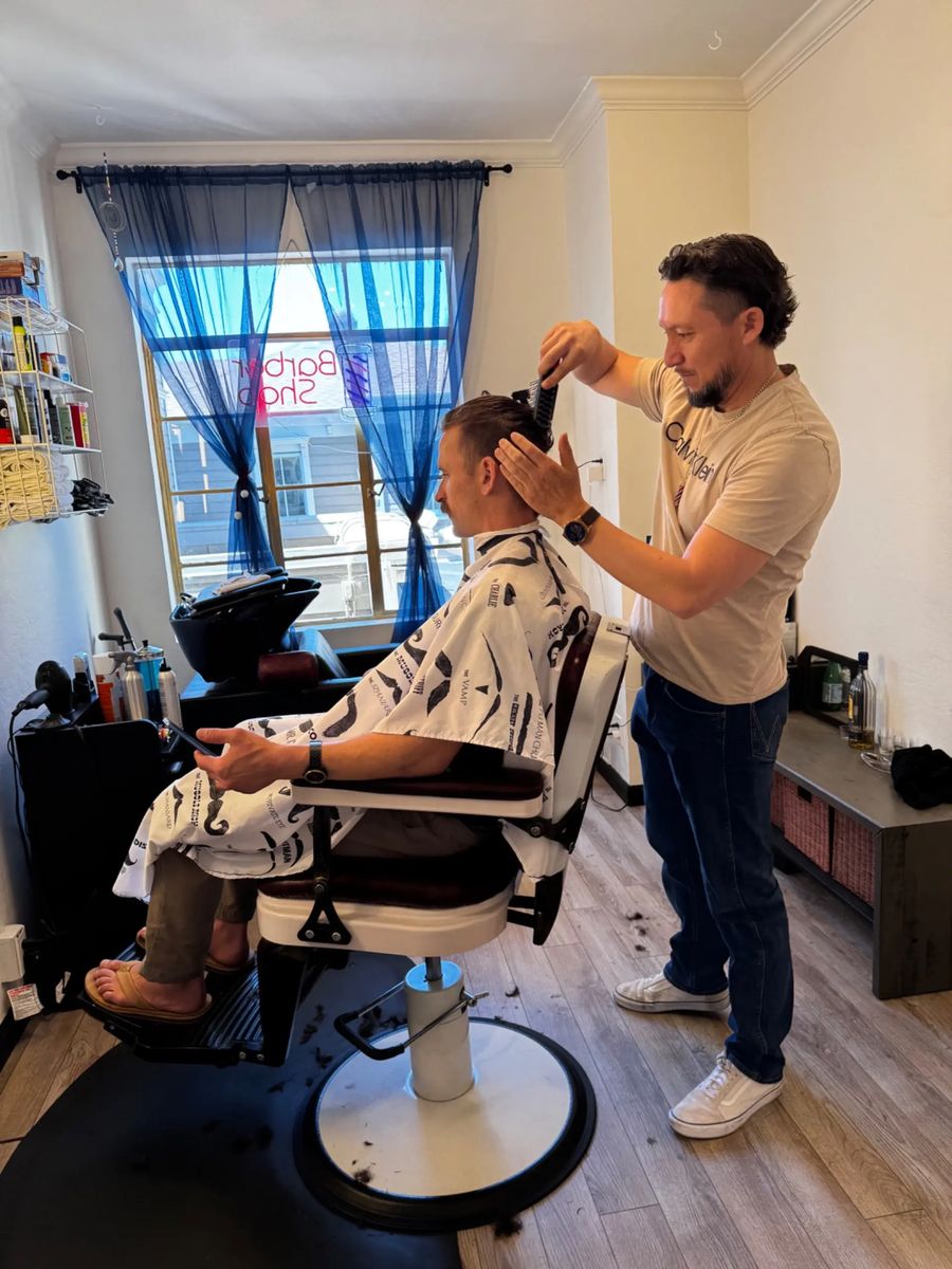 JP cutting a client’s hair in the sunlit private studio, with the shampoo station behind them