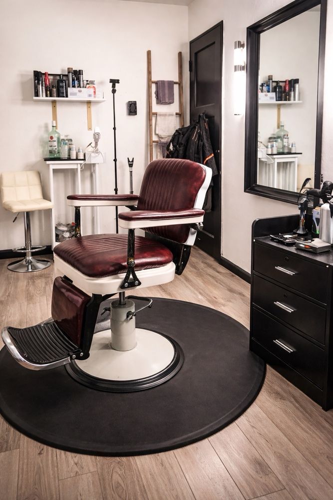 The studio’s single barber chair on a round mat, with a large black mirror and product shelves
